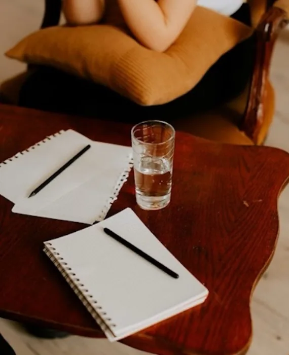 A calm therapy room with a notebook, pen and glass of water on a wooden table